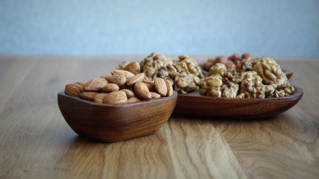 Walnuts and almonds in wooden bowl on wooden table, shallow depth of fieldの写真素材