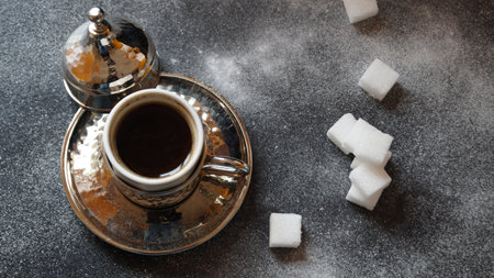 Cup of coffee with sugar cubes on dark background, top viewの写真素材