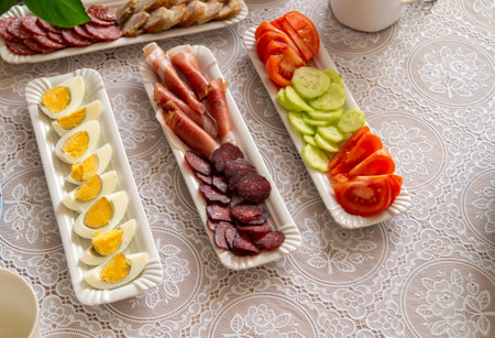 Plate with different sausages, eggs and vegetables on tableの写真素材
