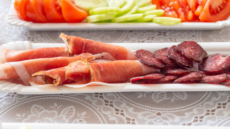 Plate of sausages, ham, salami and vegetablesの写真素材