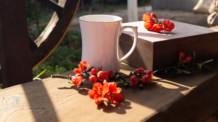 Cup of coffee and flowers on a wooden table in the sunlightの写真素材