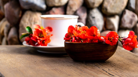 Cup of coffee and red flowers on a wooden table with stonesの写真素材