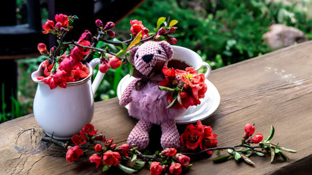 Cup of tea with crocheted bear and flowers on wooden tableの写真素材