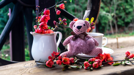 Cup of tea and toy bear on a wooden table in the garden