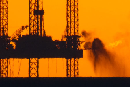 Drilling platform in the port. Oil platform at sunset with a burning torch. Towing of the oil...