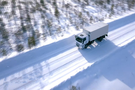 A lorry with a wagon rides along the road in winter. Winter road for a truck.の写真素材