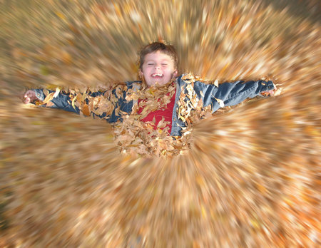 Very happy boy playing in autumn leaves