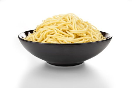 Black ceramic pasta bowl overflowing with noodlesの写真素材