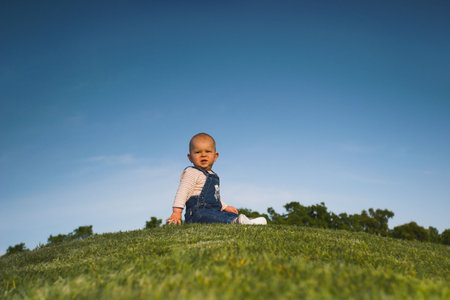 Stop the world - I want to get off. Baby is sitting on a hill, looking back and makes a scared face like someone who has enough of something.の写真素材