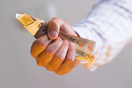 Businessman holds euro bank notes in hand.の写真素材