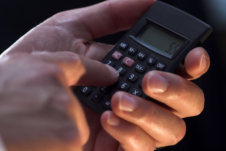 A male hand is using a simple calculator.の写真素材