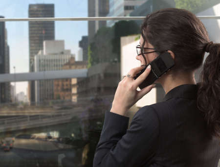 Young businesswoman talks on a mobile phone in her very exclusive office in the downtown.の写真素材