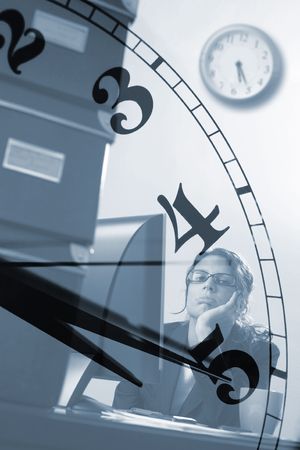 Bored young female officeworker thinks of the time when business hours end.の写真素材