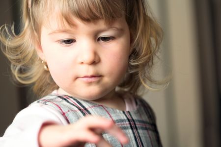 A young, 18 months old girl looks at her little hand.の写真素材