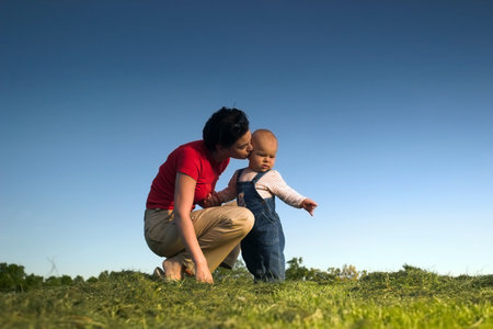Baby and his mother are having outdoor fun together and they are smiling a lot. There are nice...