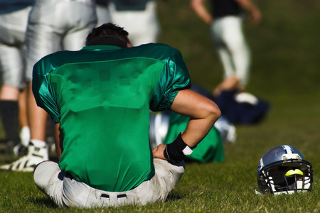 A tired football player is taking rest after the game.の写真素材