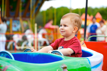 Two years old child driving toy vehicle in the amusement park.の写真素材