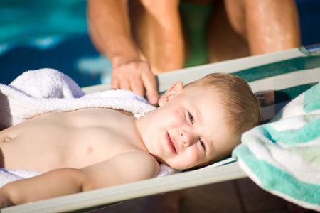 Two years old baby boy enjoys sunshine in deckchair. Natural light, summer.の写真素材
