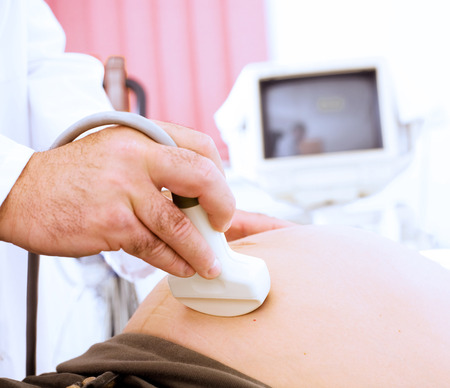 Obstetrician examining pregnant belly by ultrasonic scan.の写真素材