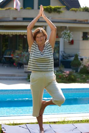 Happy active senior woman doing yoga exercise at home, smiling.の写真素材
