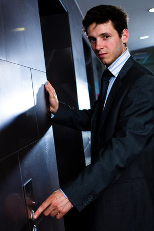 Young businessman standing at office in front of elevator.
