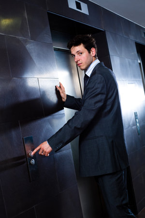 Young hapy businessman standing at office in front of elevator.