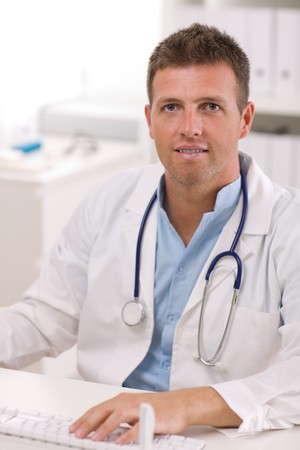 Happy male doctor working at office, smiling.の写真素材