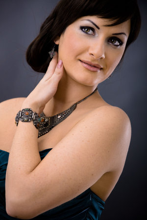 Closeup portrait of beautiful young woman wearing dark blue evening dress with necklace and bracelete, smiling and looking at camera.の写真素材