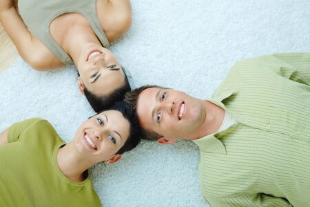 Three friends lying on floor with heads close to each other.の写真素材