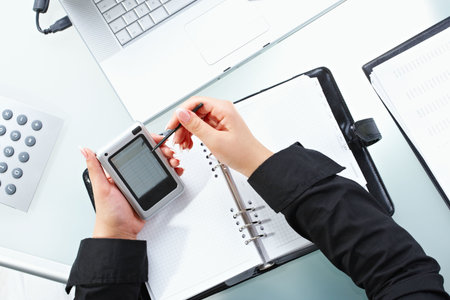Female hand using touch screen handheld computer with stylus.