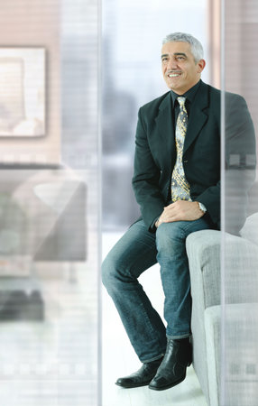 Casual businessman sitting on couch in modern office, smiling.