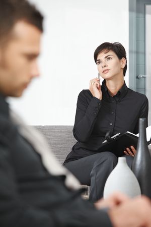 Young businesswoman sitting on sofa at office talking on mobile phone.の写真素材