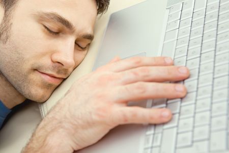 Man overslept by the keyboard of a laptop computer. eyes closed, high-angle view.  の写真素材