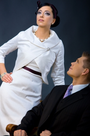 Portrait of young couple dressed in elegant clothes. Woman wearing white cocktail shirt with jacket, man wearing three-pieces dark suit, looking up.の写真素材