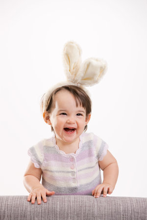 Closeup portrait of happy baby girl in easter bunny costume, laughing. Isolated on white background.