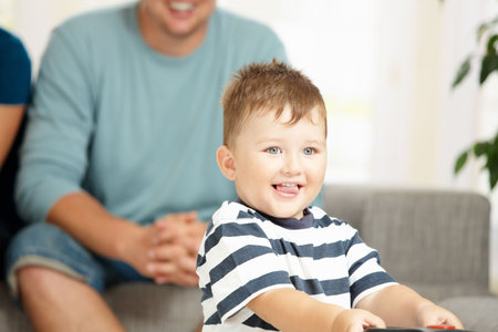Portrait of happy little boy at home with his parents in background. Selective focus on child.