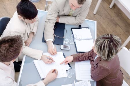 High-angle view of businesspeople having a meeting at office, sitting around the desk and talking.の写真素材