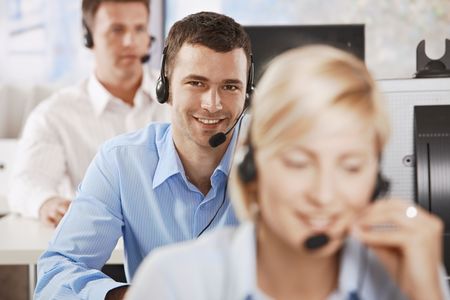 Young customer service operator talking on headset, smiling.の写真素材
