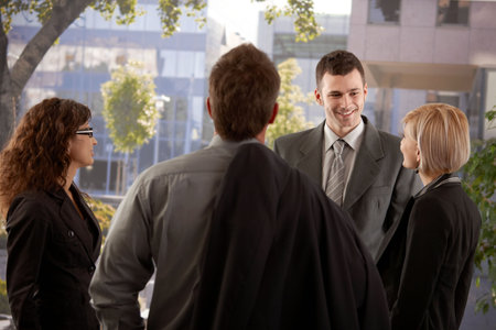 Group of young businesspeople talking in front of of office building. 