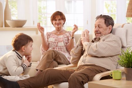 Grandparents with grandson sitting in living room at home having fun together.の写真素材