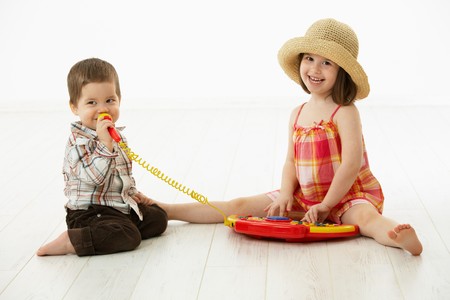 Happy kids playing on toy music instrument, little boy singing to microphone over white background.の写真素材