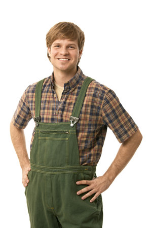 Confident young worker wearing green workwear, standing with arms on hips, smiling. Cutout.の写真素材