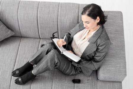 Young businesswoman sitting on sofa, working, overhead view.の写真素材