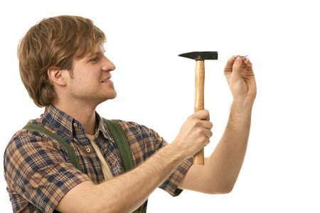 Young man hammering nail, profile view. Isolated on white.の写真素材
