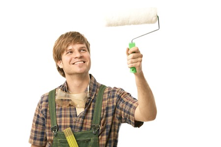Young man painting wall using paint roller, smiling. Isolated on white.の写真素材
