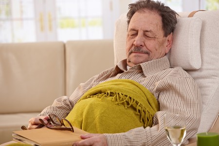 Senior man lying in armchair, fell asleep while reading book.の写真素材