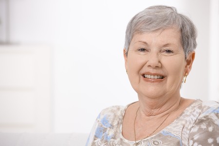 Portrait of happy senior woman at home with gray hair looking at camera, smiling.の写真素材
