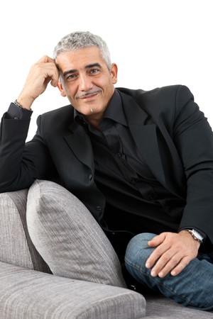 Portrait of mature man sitting on sofa, smiling, isolated on white background.の写真素材