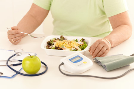 Elderly woman eating healthy diet, salad and apple.