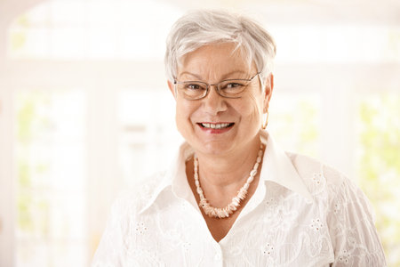 Closeup portrait of happy senior woman with glasses, looking at camera, smiling.の写真素材